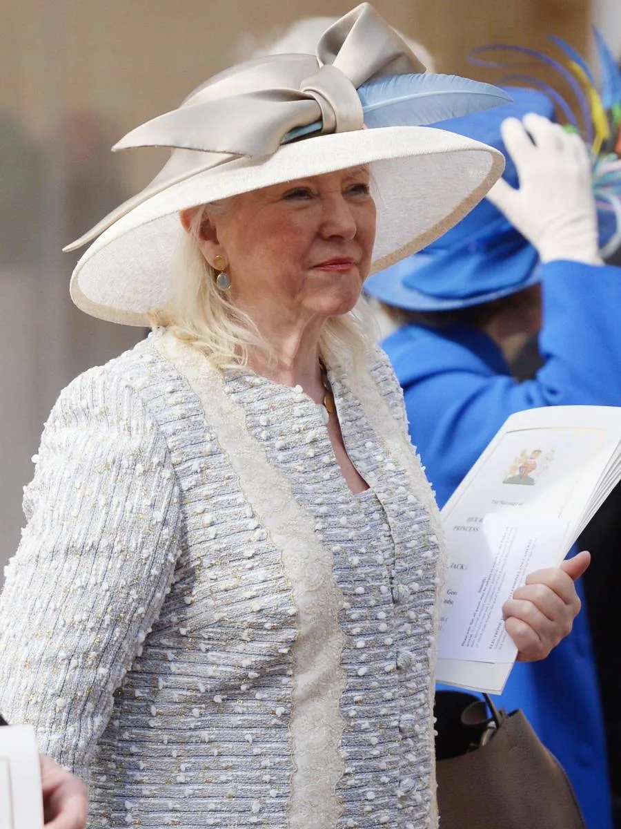 Angela Kelly standing next to an exhibition of Queen Elizabeth II's outfits.